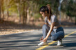 © Wasana - A woman is kneeling on the road, tying her shoes