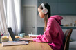 © Home-stock - Distance education. Lady teenager in wireless headphones studying online on laptop computer at home, side view. Schoolgirl make homework assignment