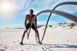 © Ramba/peopleimages.com - Athlete, fitness and battle ropes on beach for exercise, workout and cardiovascular health outdoor. Black man, wellness and high intensity training by ocean with sun, spiral and slam for strength