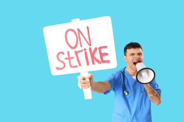 Protesting male doctor holding placard with text ON STRIKE and shouting into megaphone against blue background