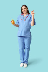 Sticker - Beautiful young pregnant doctor holding jar with fish oil pills pointing at something on blue background