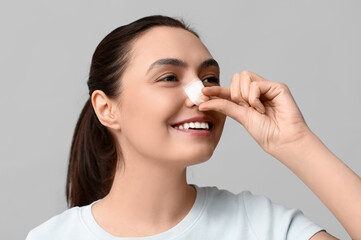 Poster - Young woman with bandaged nose on grey background. Plastic surgery concept