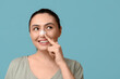 © Pixel-Shot - Young woman pointing at bandaged nose on blue background. Plastic surgery concept