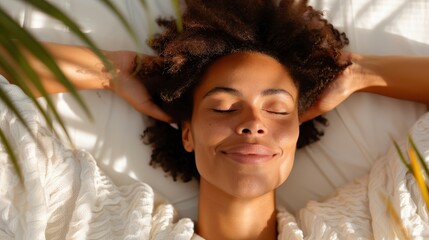 Wall Mural - A close-up of a woman lying in bed with her eyes closed and a peaceful smile, her arms behind her head, enjoying the warmth of the bright morning light through windows.