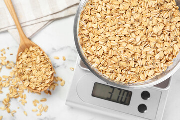 Sticker - Kitchen scale with bowl of dry oats and spoon on white marble table, flat lay