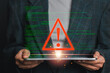 © Satori Studio - A person holding a tablet with a red warning symbol and green code lines, symbolizing a data breach and cybersecurity threat.