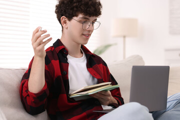 Canvas Print - Teenager with notebooks and pen working on laptop at home. Remote job