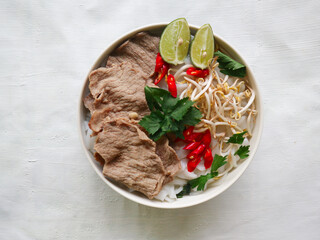 Wall Mural - A Bowl Pho Bo traditional Soup with beef, rice noodles, ginger, lime, chili pepper in bowl. Close up. Vietnamese cuisine served on black background