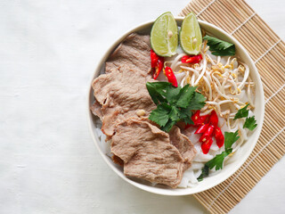 Wall Mural - A Bowl Pho Bo traditional Soup with beef, rice noodles, ginger, lime, chili pepper in bowl. Close up. Vietnamese cuisine served on black background