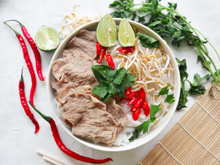 Wall Mural - A Bowl Pho Bo traditional Soup with beef, rice noodles, ginger, lime, chili pepper in bowl. Close up. Vietnamese cuisine served on black background