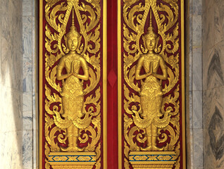 Front view of two golden yellow statues of Buddha with decoration on the wall of Wat Suwan, Bangkok, Thailand
