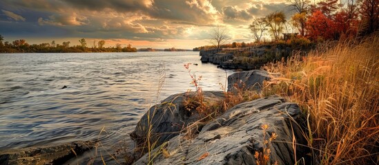 Poster - Dramatic autumn nature scene at a rocky lakeshore with space for text placement; weeds growing on riverbank rocks create a picturesque travel and camping theme.
