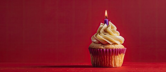 Wall Mural - A caramel cupcake topped with a lone purple candle displayed against a red background, providing ample copy space in the image.