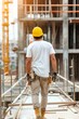 © Katsyarina - A male builder on the background of an object under construction. Construction works. Workplace. A construction site. The man in the helmet