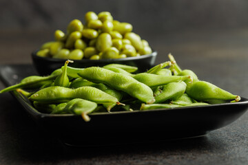 Wall Mural - Green edamame pods. Fresh soybeans on plate on black table.