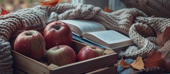 Sticker - Autumn vibes in a cozy setting with a red apple other apples in a box an open book warm scarf and copy space image