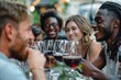 © SHI - Happy friends sitting at restaurant tables drinking red wine - multi-racial young people enjoying a rooftop dinner party together - boys and girls taking a lunch break outside the concept of food and