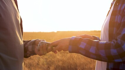 Two farmers make a crop sale in the wheat field. close-up of the farmer hand money. farmer handshake inspection. agriculture business