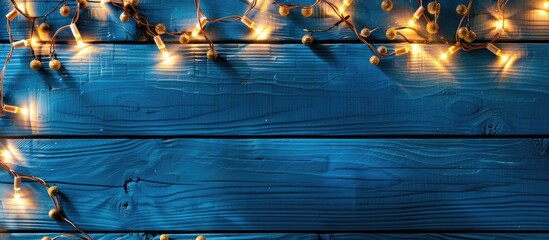 Canvas Print - Top view of Christmas garland lights on a blue wooden background with room for text in a copy space image