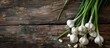 © Gular - Wooden table showcasing fresh garlic bulbs with long stalks offering ample copy space for customization