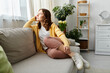 © LIGHTFIELD STUDIOS - Middle aged woman sitting on a cozy couch in a stylish living room.