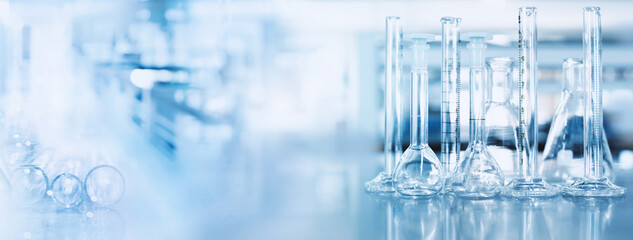 Wall Mural - glass flask and cylinder in chemistry science lab blue banner background