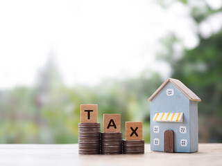 Poster - Miniature house and Wooden blocks with the word TAX on stack of coins. The concept of payment tax for house, Property investment, House mortgage, Real estate