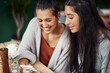 © TasJam/peopleimages.com - Girl, teenager and sisters in coffee shop, phone and texting with reunion for memory, listening or gossip. Family, smile and conversation with drink, tea and chat with funny meme, bonding and care