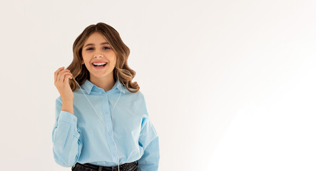 Image of a happy young beautiful woman posing isolated over white wall background listening music with earphones.