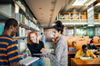 © Marko Geber - Diverse students studying and talking in library next to bookshelves
