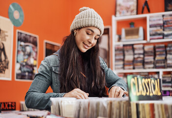 Teenager, shopping and vinyl in record store with music, vintage and retro song search. Young woman, retail shop and gen z student with browsing for second hand audio and thrift collection on sale