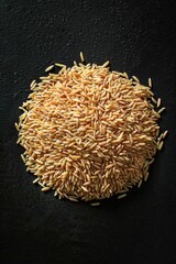 A pile of brown rice sitting on a dark, flat surface