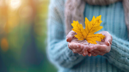 Woman holding yellow oak leaf close-up in hand in fall season - autumn and nature concept