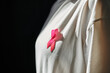 © LIGHTFIELD STUDIOS - A close-up of a pink ribbon pinned to a woman's shirt, symbolizing breast cancer awareness.