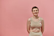 © LIGHTFIELD STUDIOS - A woman with short hair smiles confidently, wearing a pink ribbon in support of breast cancer awareness.