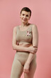 © LIGHTFIELD STUDIOS - A brave woman with short hair wearing a bra adorned with a pink ribbon, symbolizing breast cancer prevention and awareness.