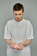 © LIGHTFIELD STUDIOS - A woman with short hair holds a pink ribbon in her hands against a grey background.