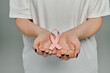 © LIGHTFIELD STUDIOS - A woman holds a pink ribbon in her cupped hands, signifying breast cancer awareness.