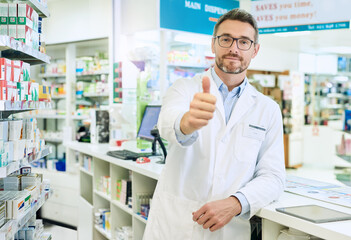 Wall Mural - Happy man, portrait and pharmacist with thumbs up for healthcare, pharmaceutical or medical supplies at pharmacy. Mature male person with like emoji, yes sign or ok for good review, vote or thank you