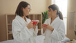 © Krakenimages.com - Two women in a spa wearing bathrobes, enjoying a relaxing moment with coffee in a wellness center lounge.