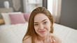 © Krakenimages.com - A young, smiling, caucasian woman lounges in her well-lit bedroom, exuding casual beauty and comfort.
