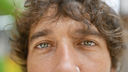 Wall Mural - Close-up portrait of a handsome hispanic man with curly hair outdoors in a city environment.