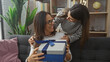 © Krakenimages.com - A mother and daughter sharing a joyful moment with a gift in a cozy living room, exemplifying family love and togetherness.
