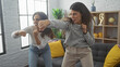 © Krakenimages.com - Two women playfully boxing in a modern living room, exuding happiness and closeness.