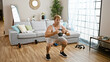 © Krakenimages.com - A muscular man squats with a kettlebell in a tidy living room, showcasing home workout and fitness.