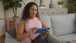 © Krakenimages.com - Mature woman relaxing on a sofa in a home living room, engaged with a tablet, surrounded by modern decor and indoor plants.