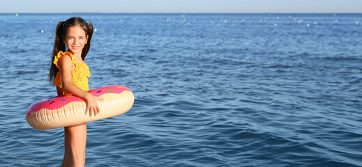 Sticker - Cute little girl with inflatable ring on sea beach