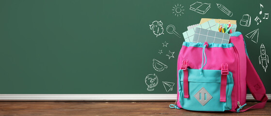 Wall Mural - Colorful school backpack with notebooks and pencils on wooden table near green chalkboard