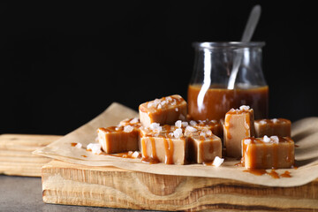 Wall Mural - Tasty candies, caramel sauce and salt on grey table, closeup