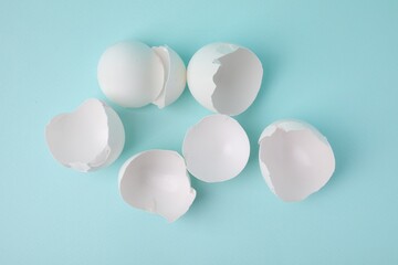 Wall Mural - Broken eggshells on light blue background, top view